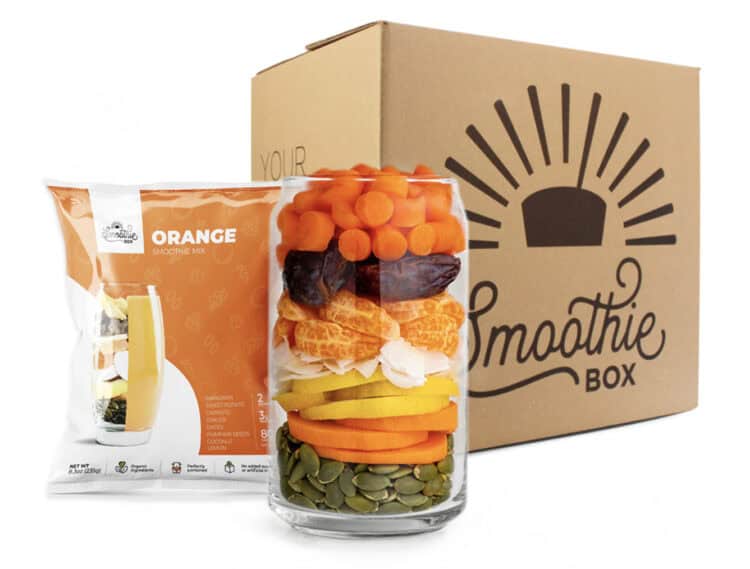 Smoothiebox with a glass of fruit and vegetables next to a smoothie pack.